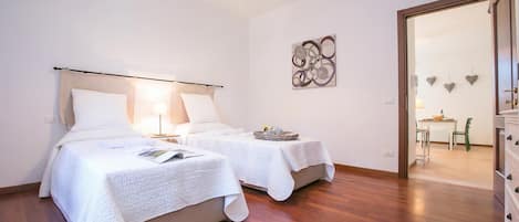 Habitación de hotel con dos camas, un comedor y un pasillo.