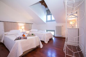 A bedroom with two beds, a skylight, a radiator, and a white metal shelf unit. - Casa Al Prato Apt. G (Varenna)