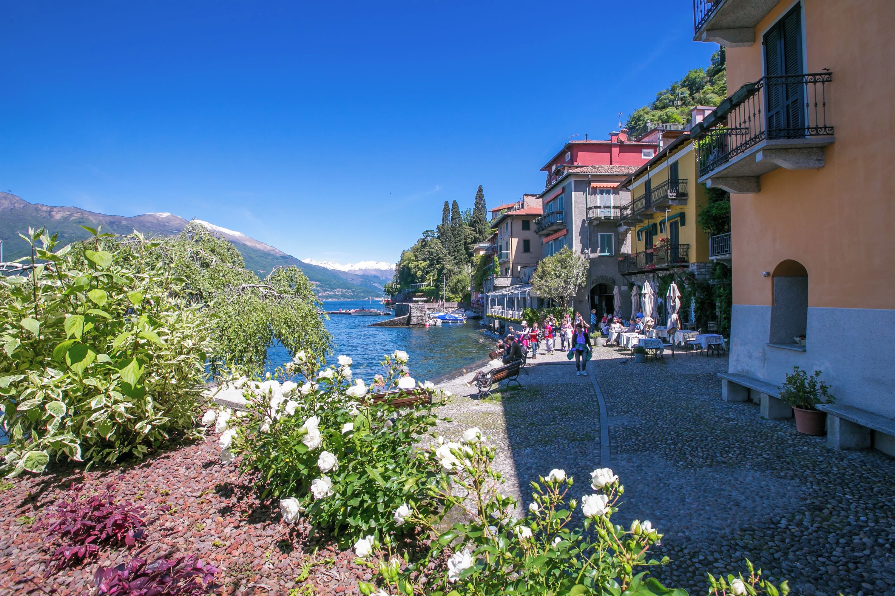 Un patio junto al lago con suelo de piedra, mobiliario exterior y vistas al lago y a las montañas.