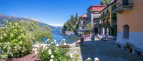 Un patio junto al lago con suelo de piedra, mobiliario exterior y vistas al lago y a las montañas.