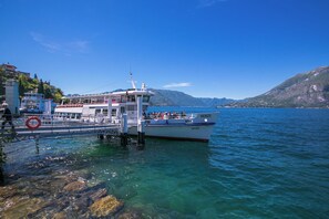 A boat docked at a pier with clear water and mountains in the background.