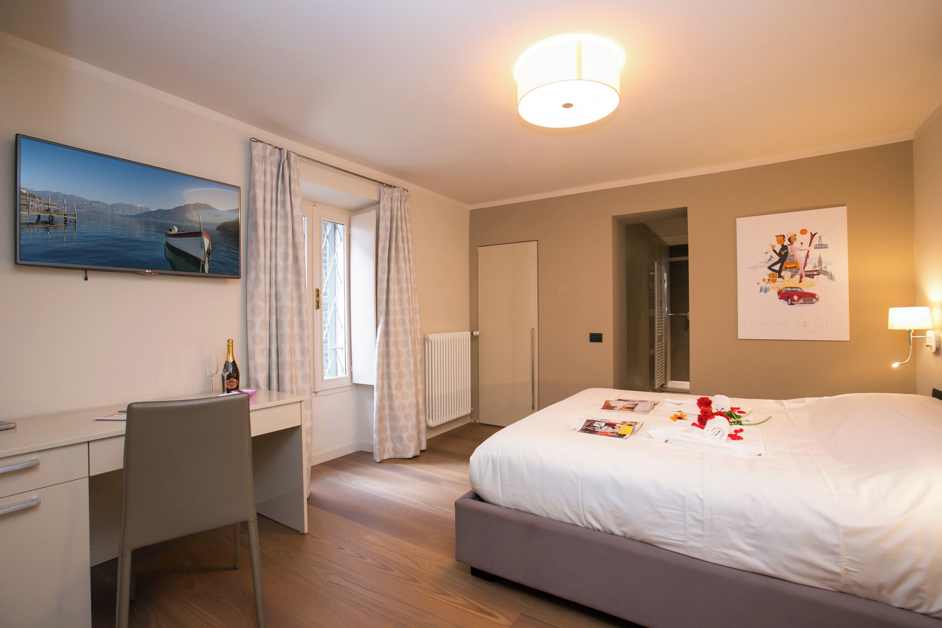 Ein Hotelzimmer mit Bett, Schreibtisch, Stuhl, Fernseher und einem Fenster mit Vorhängen.