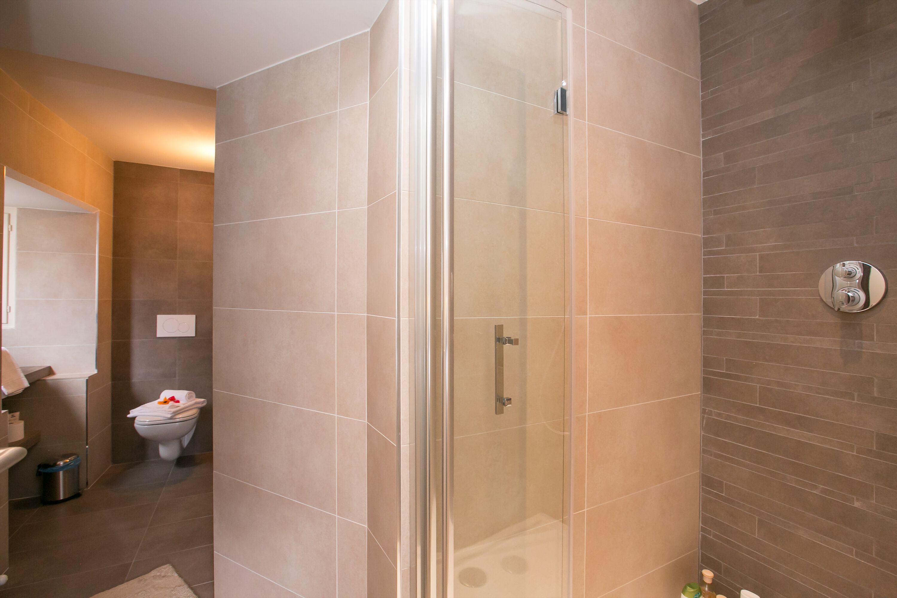 Un baño moderno con ducha envuelta en vidrio, inodoro y lavamanos.