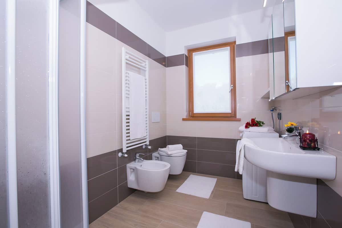 A modern bathroom with a bidet, toilet, sink, and a window.