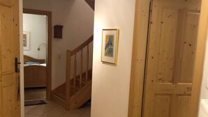 A hallway with a wooden door, a staircase, and a framed picture on the wall.