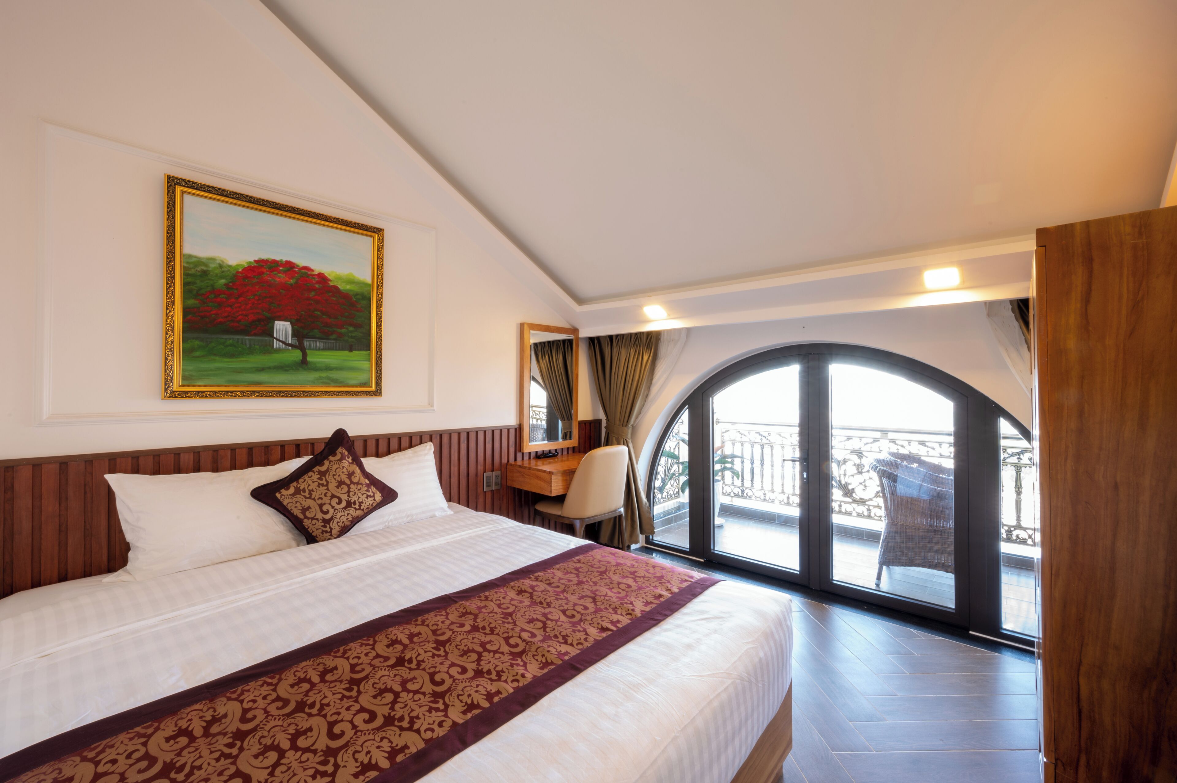 Una habitación de hotel con una cama grande, un escritorio y un balcón con vistas.
