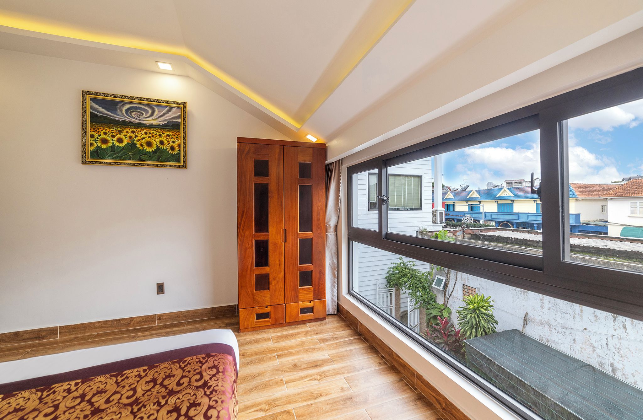 Una habitación con un ventanal grande, una puerta de madera, una cama y un cuadro en la pared.