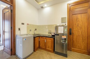 Eine kompakte Küche mit Kühlschrank, Waschmaschine, Holzschränken und Spüle.