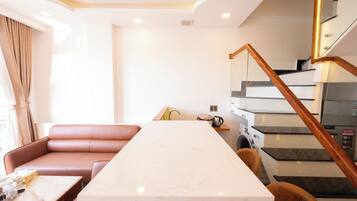 A modern kitchen with a marble countertop, a built-in oven, and a staircase with wooden railings.