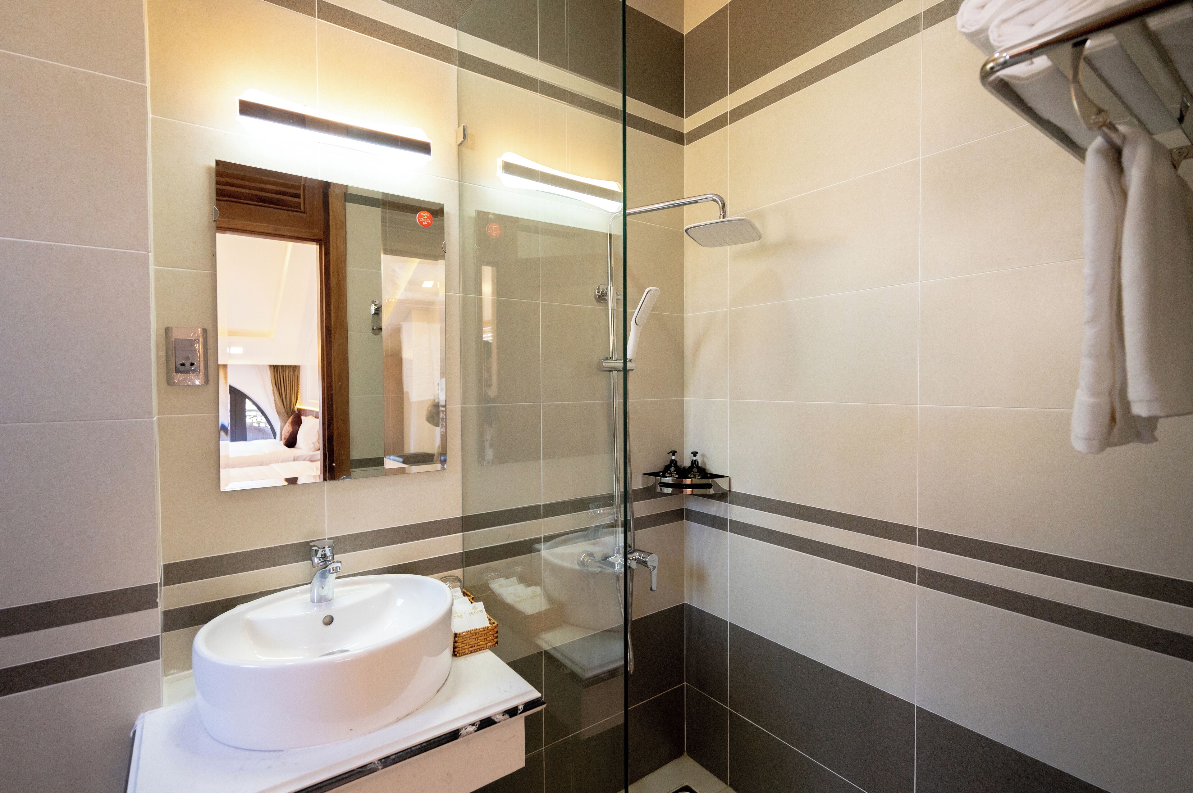 A modern bathroom with a glass-enclosed shower, a white sink, and a mirror.