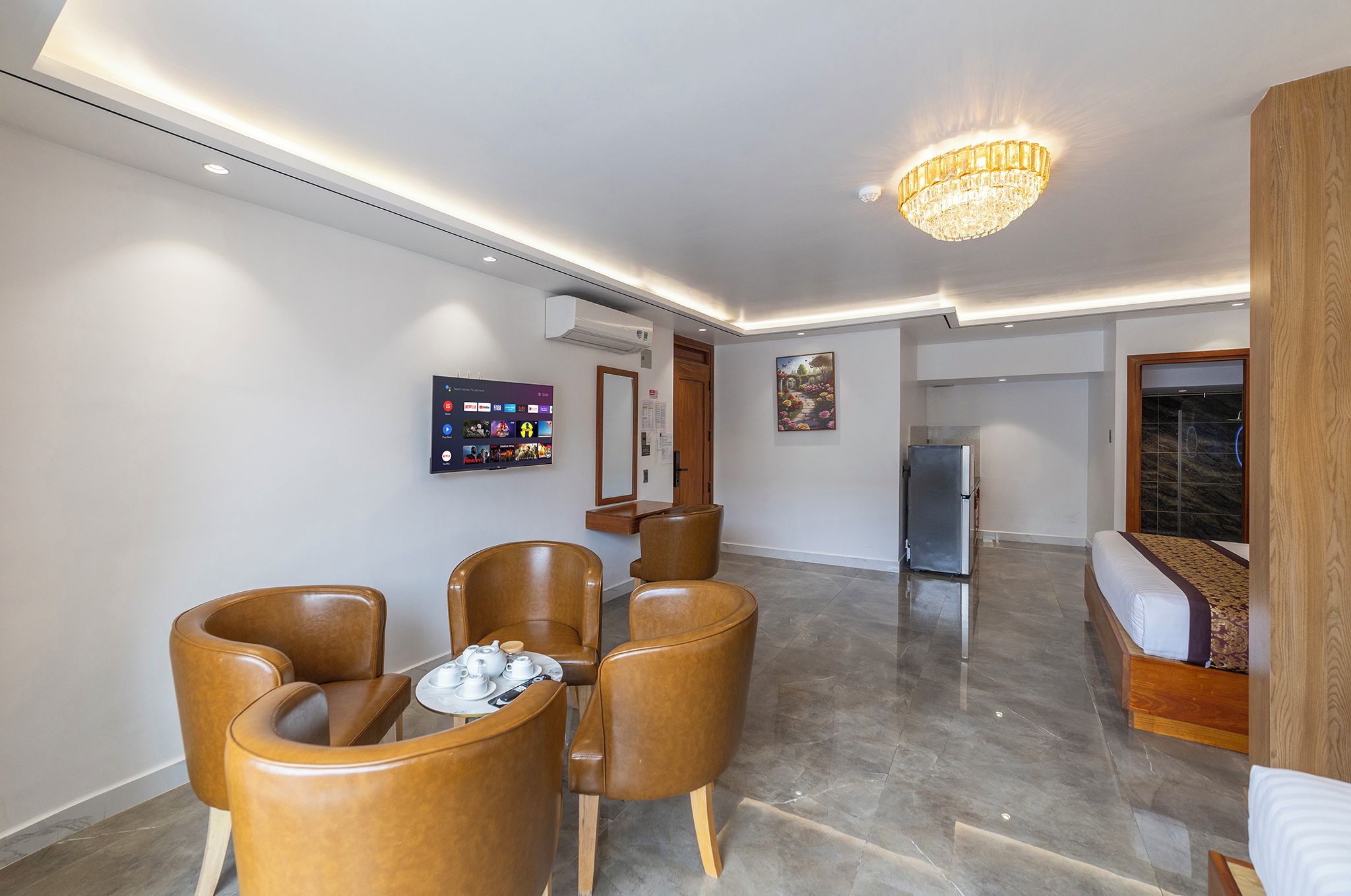 Ein modernes Wohnzimmer mit Flachbildfernseher, einer Kristallleuchter und einem Essbereich mit Stühlen und Tisch.