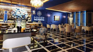 Zona de bar con decoración azul y dorada, un candelabro y una barra con varios objetos.