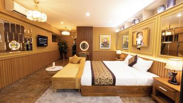 Habitación de hotel con una cama grande, una mesita de noche, un televisor, un espejo y un panel decorativo en la pared.