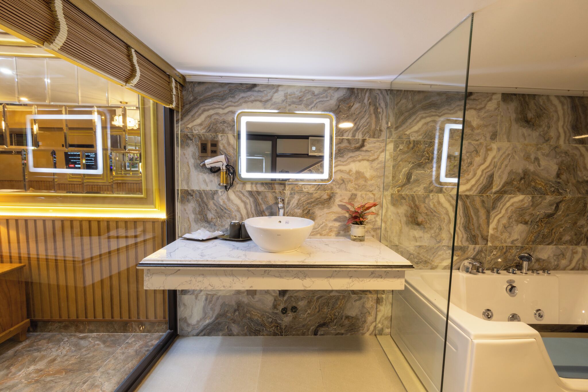 A modern bathroom with a marble vanity, a large mirror, and a separate bathtub.