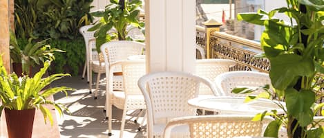 A terrace with white wicker chairs and potted plants.
