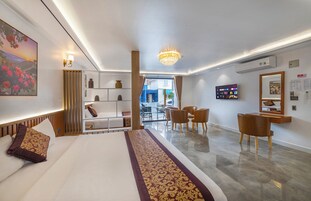 A hotel room with a bed, a desk, a television, and a view of the street.