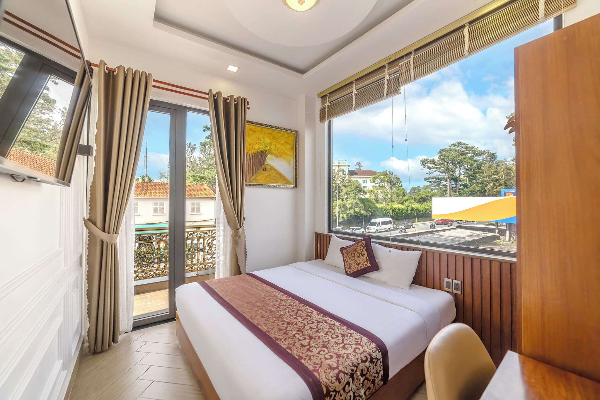 Quarto de hotel com cama, escrivaninha e vista para a cidade.