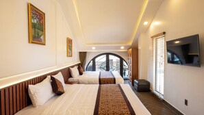 Habitación de hotel con dos camas, televisión y balcón con vistas.