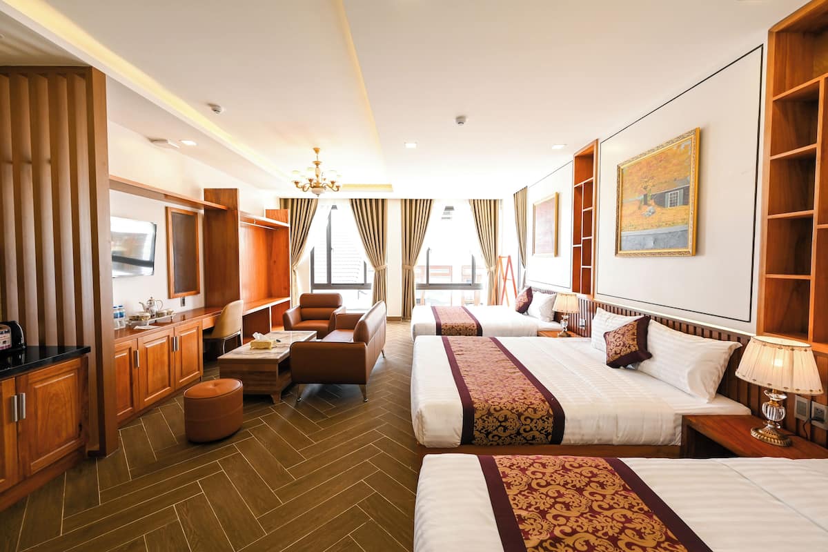 A hotel room with two beds, a desk, a chair, a TV, and a large window.