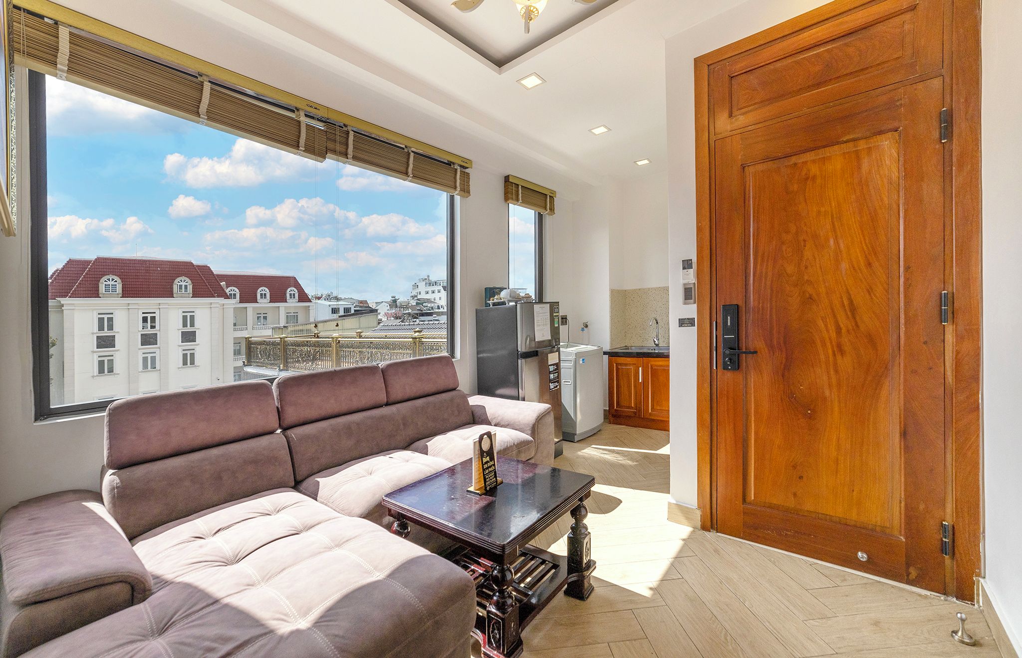 A modern living room with a sofa, a coffee table, and a view of the cityscape through large windows.