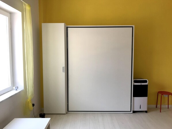 Ein Zimmer mit Schiebetür, einem kleinen Tisch, einem Stuhl und einem Fenster mit Vorhang.