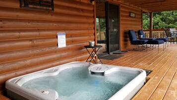 A hot tub on a wooden deck with a sign about hot tub safety rules.