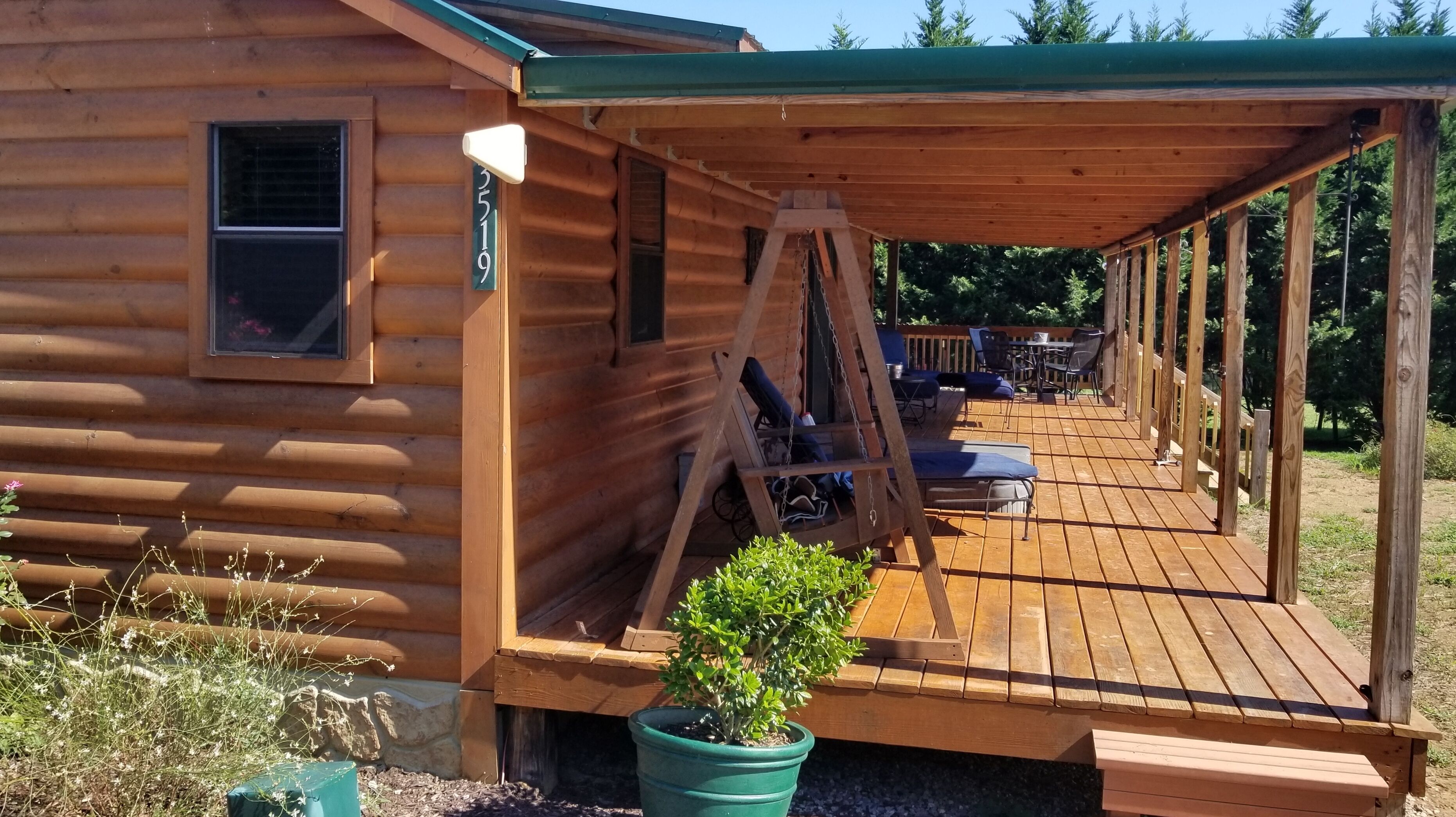 A wooden cabin with a covered porch, a swing, and a small garden area.