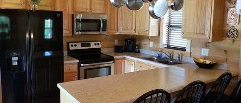 A kitchen with wooden cabinets, a black refrigerator, stainless steel appliances, and a granite countertop.