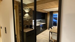 Eine moderne Küche mit einer Wand aus Stein, ein Essbereich mit einem Holztisch und Stühlen, und ein großer Spiegel, der den Raum widerbildet.