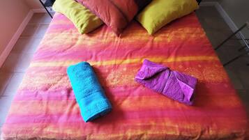 Un lit avec une couvre-lit aux couleurs vives et deux serviettes enroulées.