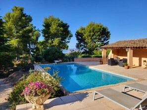 Una piscina con acqua cristallina, circondata dal verde e da una zona relax coperta.