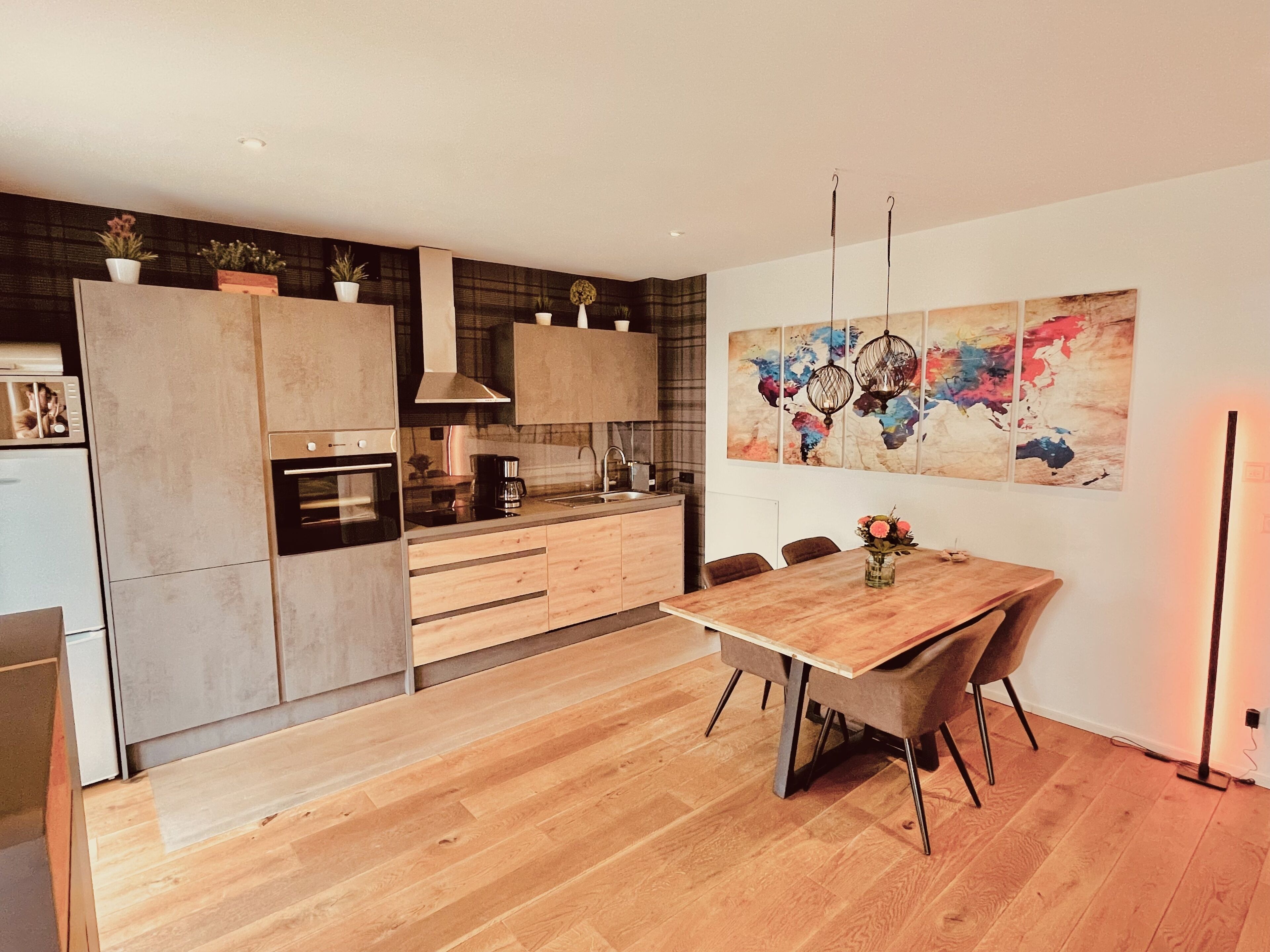 Une cuisine moderne avec des meubles en bois, une table à manger et un tableau abstrait aux couleurs vives accroché au mur.