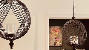 Un intérieur moderne avec deux lampes sphériques suspendues, un tableau au mur et un canapé à l’arrière-plan.