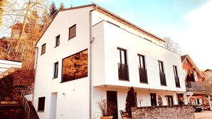 Un bâtiment moderne à deux étages, doté d’une façade blanche, de nombreuses fenêtres et d’un mur en pierre à sa base.