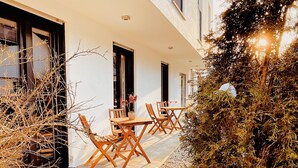 Une terrasse extérieure avec une table et des chaises, une plante en pot et un petit arbre.