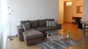 Een moderne woonkamer met een bruine modulaire bank, een glazen salontafel en een kamerkleed met patroon.