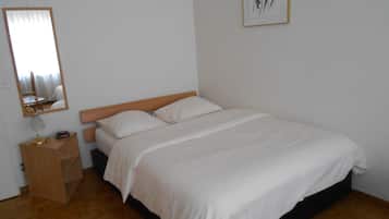 A bedroom with a bed, a bedside table, a mirror, and a framed picture on the wall.
