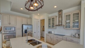 A modern kitchen with white cabinetry, a central island, stainless steel appliances, and a decorative wooden bowl.
