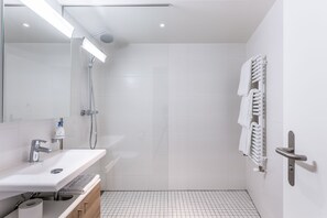 A modern bathroom with a white sink, mirror, and shower.