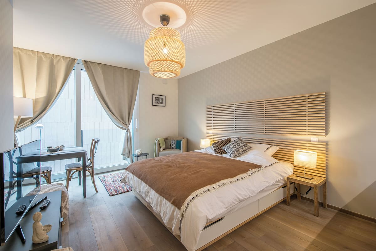 A modern bedroom with a large bed, bedside tables, a desk, and a chair.