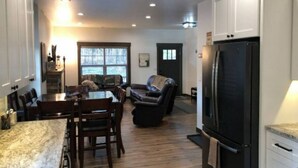 A modern kitchen with a dining area, a black refrigerator, and a cozy seating area with a fireplace.