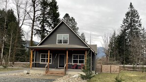 A two-story house with a porch, a front door, and a small front yard with gravel and grass.