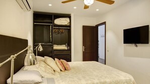 Un dormitorio con cama, lámpara de noche, armario y televisor.
