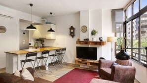 Un apartamento moderno con cocina, comedor, sala de estar y un amplio ventanal con vista a la ciudad.