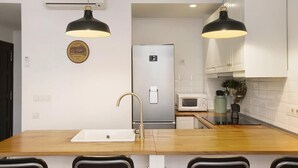 Una cocina moderna con encimera de madera, electrodomésticos de acero inoxidable e iluminación colgante.
