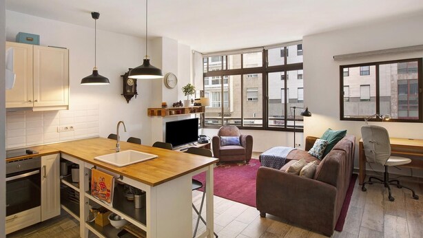 Un apartamento moderno con cocina, comedor y sala de estar. Cuenta con ventanas amplias, una chimenea y un rincón de descanso acogedor.