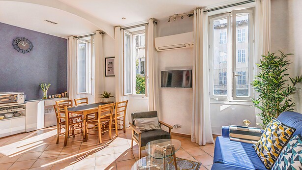 Una sala de estar moderna con comedor, un sofá, un televisor y un ventanal grande.