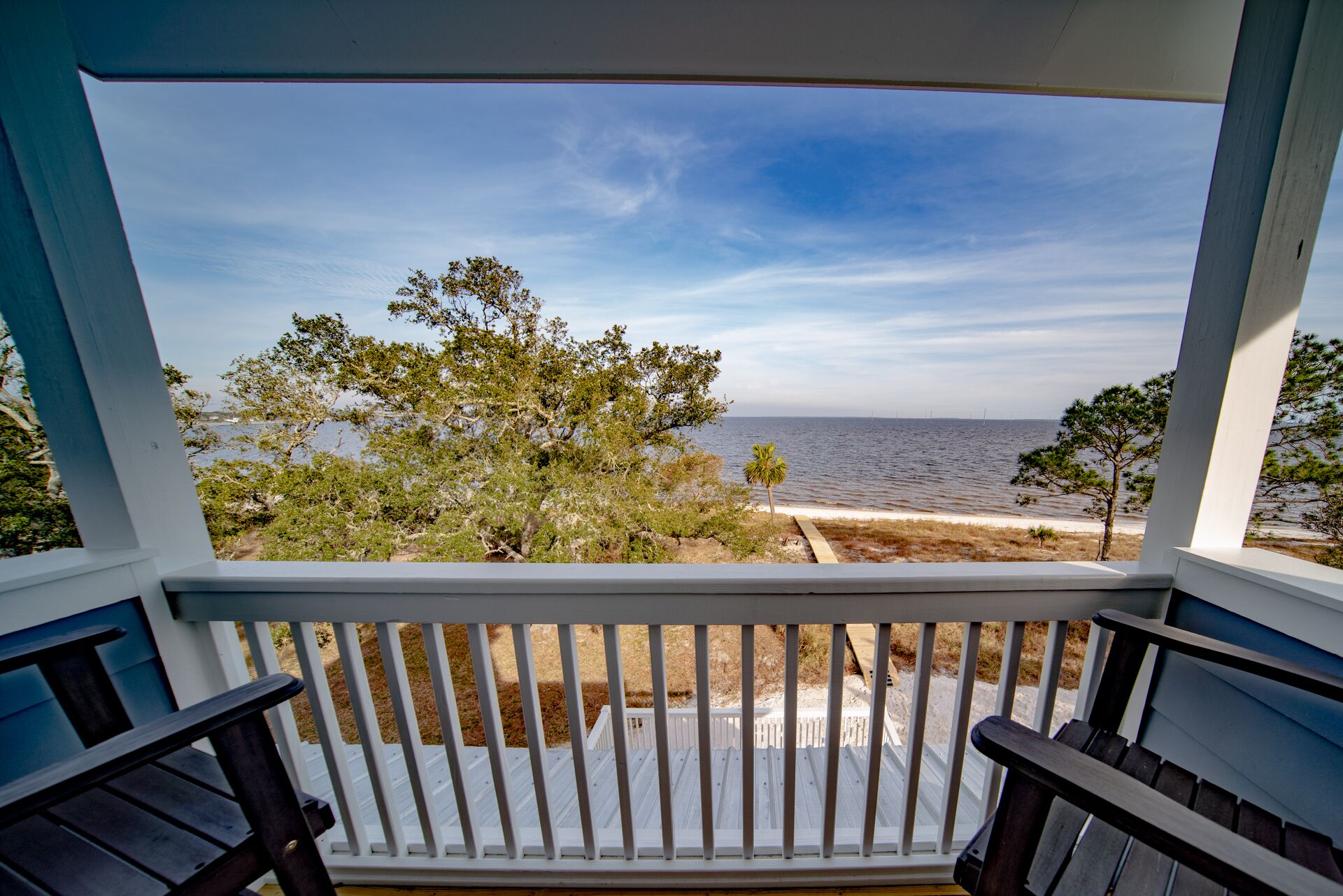 A balcony with a view of the sea and trees.
