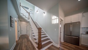 Une cuisine moderne dotée d’un réfrigérateur en acier inoxydable, d’un plancher en bois et d’un escalier menant à un autre niveau.