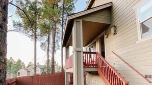 A house with a covered porch, a red staircase, and a stone wall. - Mountain View with Hot Tub/AC nestled in the pines  (Flagstaff)